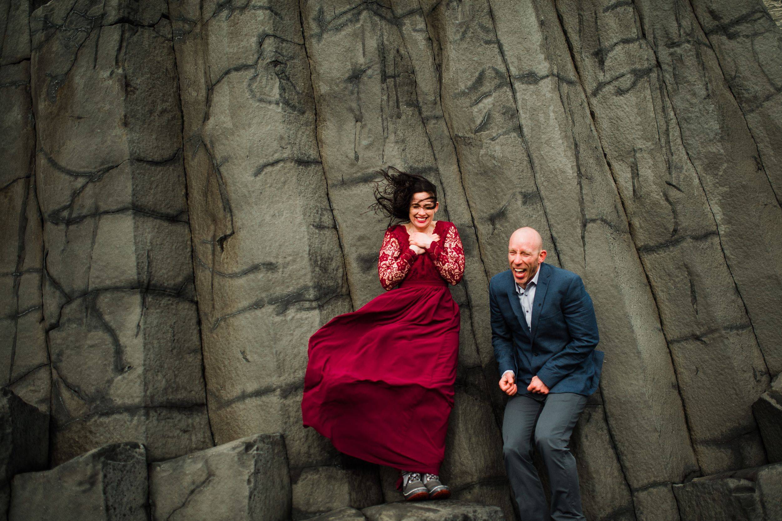 Joyful couple laughing by dramatic basalt columns in Icelands volcanic landscape.