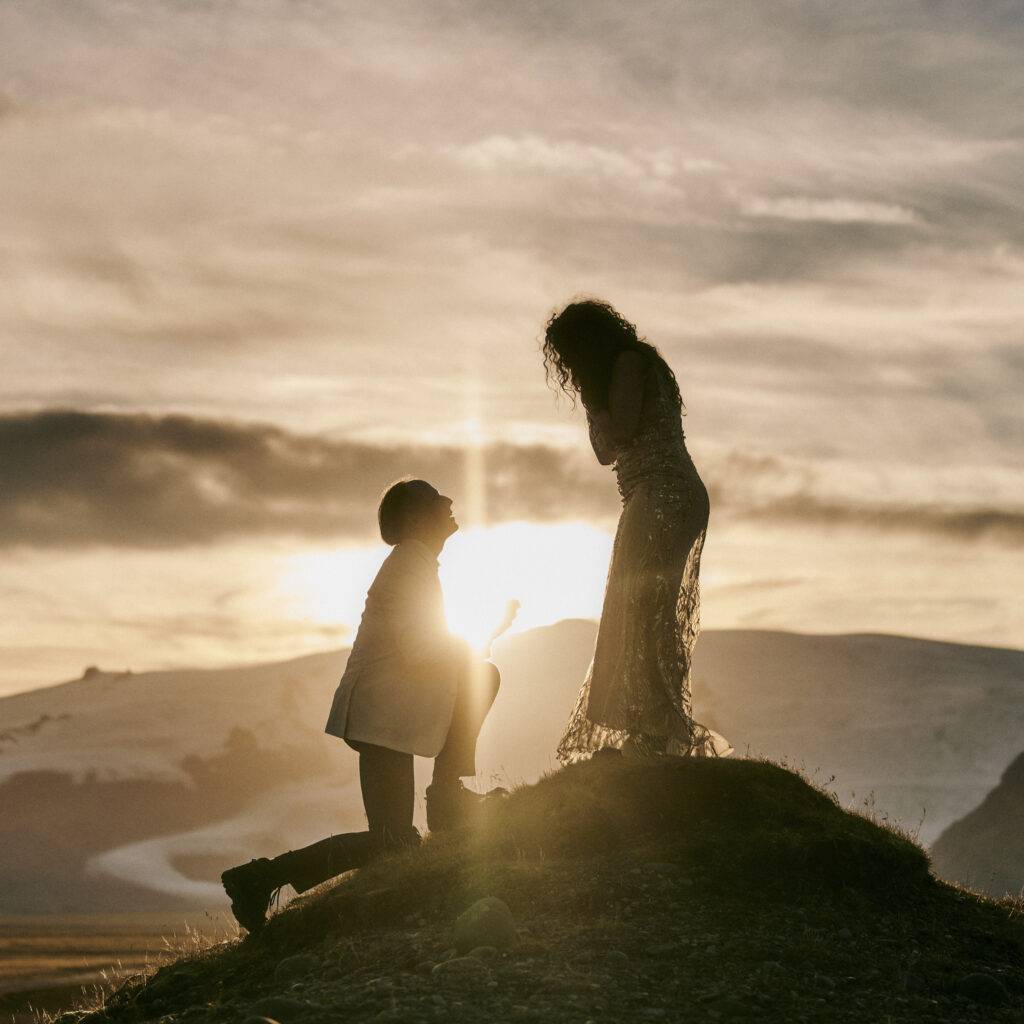 Couple’s sunset proposal silhouette on icelandic hill, capturing intimate romantic moment in nature.